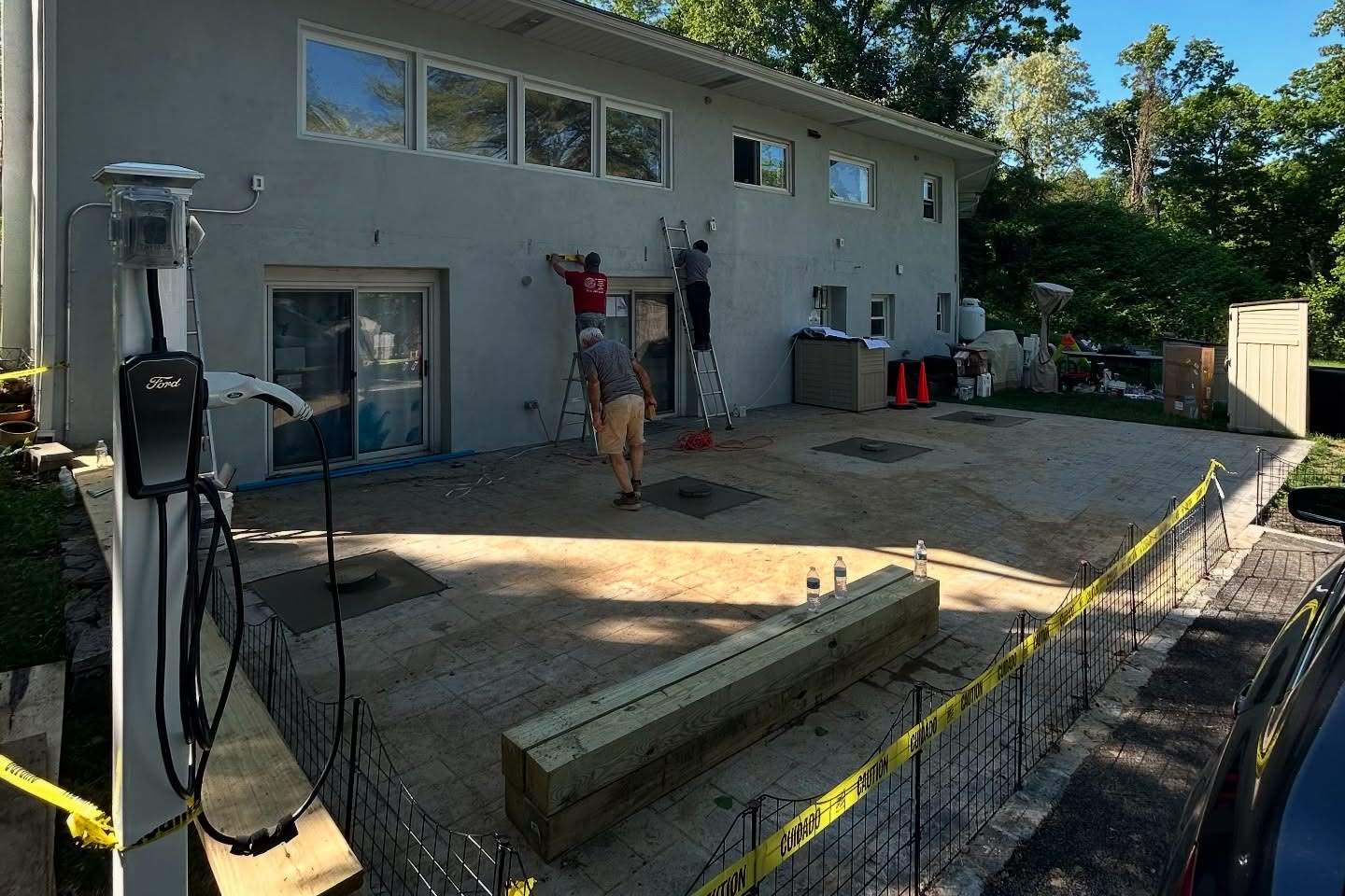 A house with a new patio and deck framing, with the crew at work, a Luxuriad project
