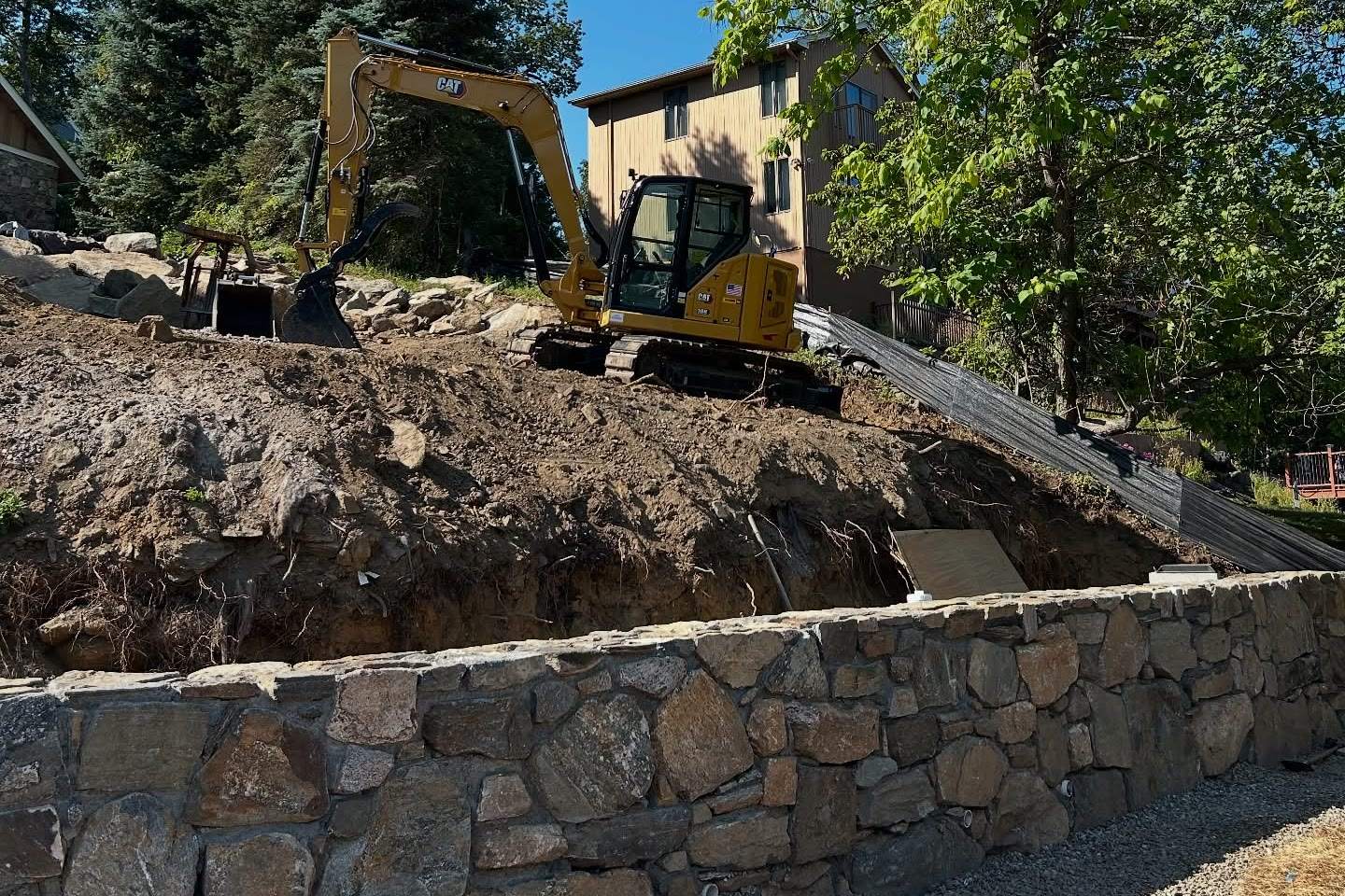 A stone retaining wall and an excavator regrading a lot, a Luxuriad project